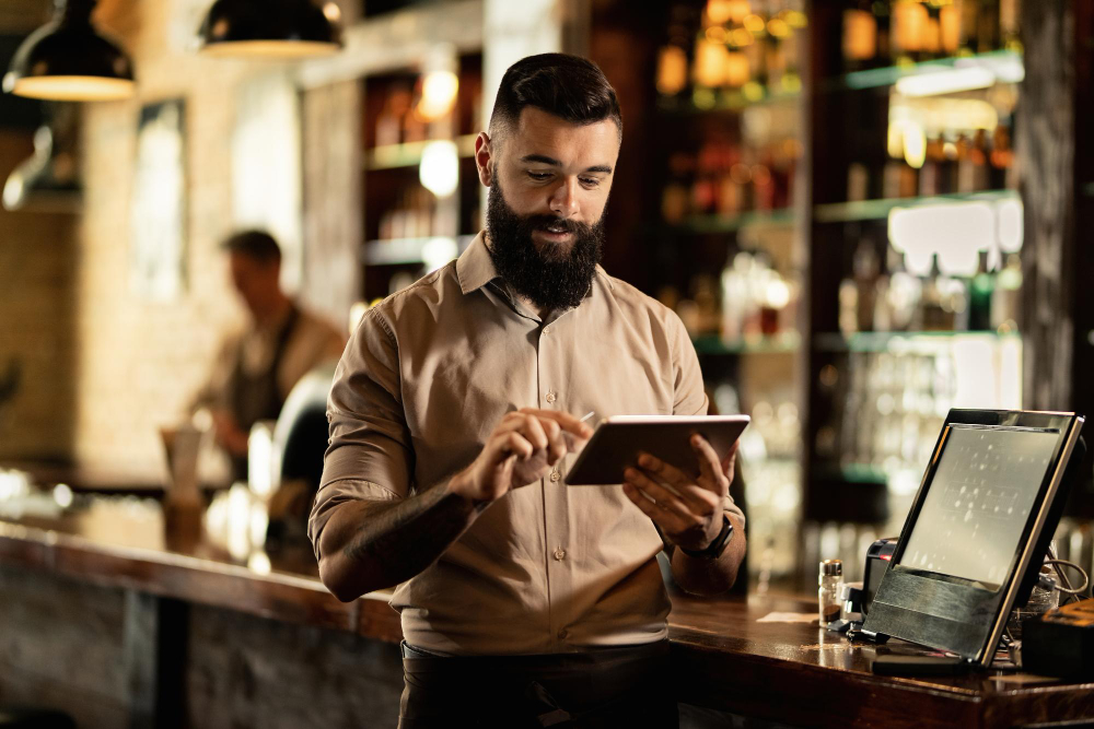 barista sonriente usando tableta digital mientras trabaja bar