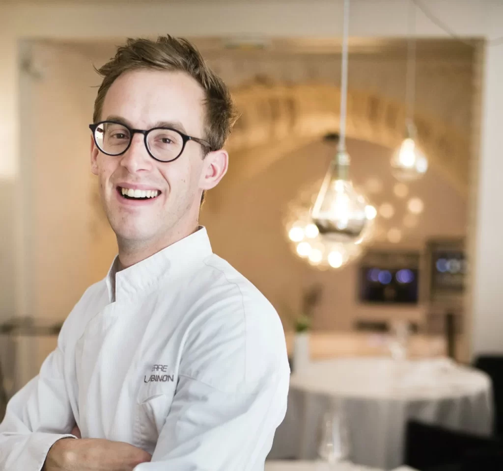 Pierre Lambinon est chef propriétaire du Py’R, à Toulouse, 2 étoiles au Guide Michelin. Pur toulousain, son parcours l’a mené de l’école hôtelière de Toulouse jusque chez Alain Ducasse à Monaco (au Louis XV), à Londres au Dorchester, puis chez Gérald Passédat à Marseille (au Petit Nice) et à Ô Saveurs à Rouffiac-Tolosan, avant de créer son propre établissement. Depuis 2013, il a adopté la réservation en ligne avec Guestonline. Pierre, présentez-nous votre restaurant, le Py’R La cuisine, pour moi, est avant tout une passion et l’amour du travail bien fait. J’ai la chance de pouvoir travailler en famille (son frère sommelier et bras droit, et sa cousine, responsable de l’administratif, ndlr), avec une équipe dévouée. Nous proposons une cuisine honnête et conviviale. Le restaurant se situe dans une vieille bâtisse toulousaine dans le centre historique de Toulouse, au 19 Descente de la Halle aux Poissons. Comment avez-vous connu Guestonline ? Un jour de 2013, Romain (chargé du marketing chez Guestonline, ndlr) est venu manger dans notre ancien restaurant. Il m’a parlé de Guestonline, une nouvelle solution de réservation en ligne. Son discours a été pour moi un déclic. J’ai compris que c’était l’outil qu’il me fallait et qui allait changer le monde de la restauration. À l’époque, il n’y avait pas encore grand monde sur le marché des nouvelles technologies dans la restauration. Pourquoi avez-vous choisi… et conservé Guestonline ? Parce que ce logiciel de gestion des réservations est génial et nous fait gagner un temps fou en salle. Il bénéficie régulièrement des mises à jour avec de nouvelles fonctionnalités et l’utilisation possible de plusieurs iPad pendant le service est très pratique pour accueillir parfaitement nos clients. Utilisez-vous une fonctionnalité en particulier ? La réservation en ligne et le fichier clients. Ce sont deux fonctionnalités très complémentaires. Le module de réservation en ligne, intégré sur notre site internet et à notre page Facebook, permet de désengorger notre ligne téléphonique et de constituer facilement un fichier clients à jour. Plus d’une réservation sur deux proviennent aujourd’hui de notre module de réservation, c’est un gain de temps énorme au quotidien. Nous notons les préférences clients dans le logiciel, ce qui nous permet d’assurer un accueil optimal et de reconnaître chaque personne. Pierre Lambinon Py-r « Une autre fonctionnalité très pratique : l’interconnexion avec notre logiciel de caisse l’Addition » – Pierre Lambinon, chef Py-r, Toulouse (31) Nous gérons la caisse et les réservations depuis un même support. Les réservations et les informations de caisse sont synchronisées en temps réel. Un gain de temps énorme, là encore. Seriez-vous prêt à revenir au cahier de réservation papier ? Impossible ! Ce serait comme re-dormir sur un matelas en paille, nous laisserions filer toutes les données de nos clients ! Voulez-vous ajouter quelque chose ? Un mot sur les équipes de Guestonline : pour dire qu’il est agréable de travailler avec vous. Convivialité, amabilité, disponibilité… sont des éléments essentiels pour notre collaboration. Pouvez-vous définir Guestonline en trois mots ? Ergonomique – Moderne – Intemporel Restaurant Le Py’R, par le chef Pierre Lambinon, 19 Descente de la Halle aux Poissons, 31000 Toulouse